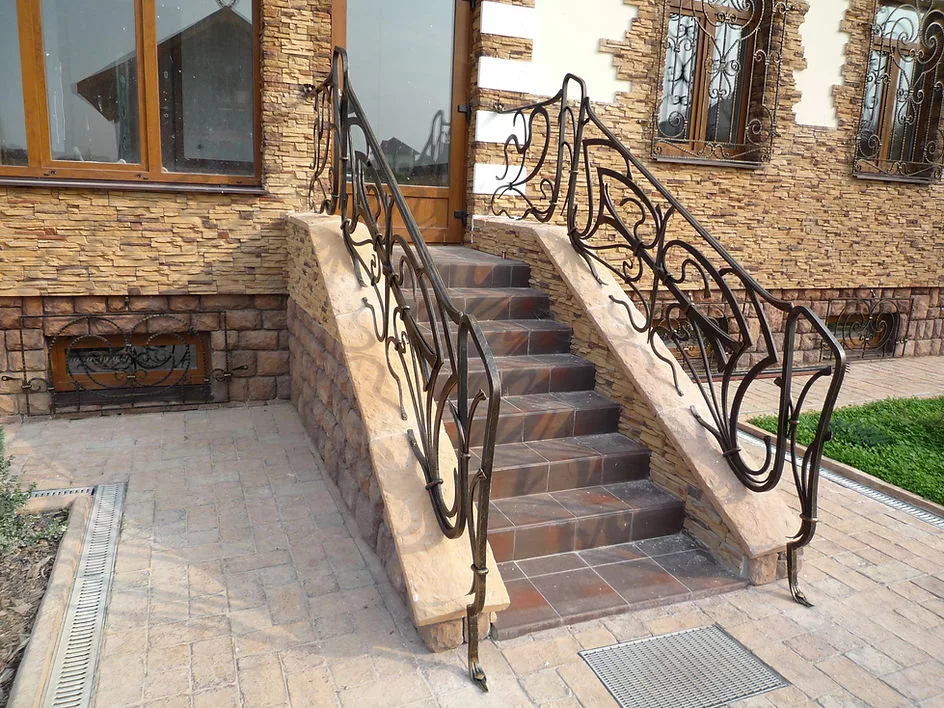 Каменная лестница с художественными перилами у дома.