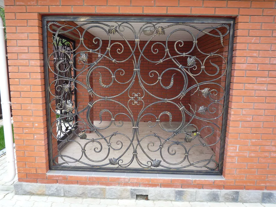Кованая решетка на кирпичной стене здания.