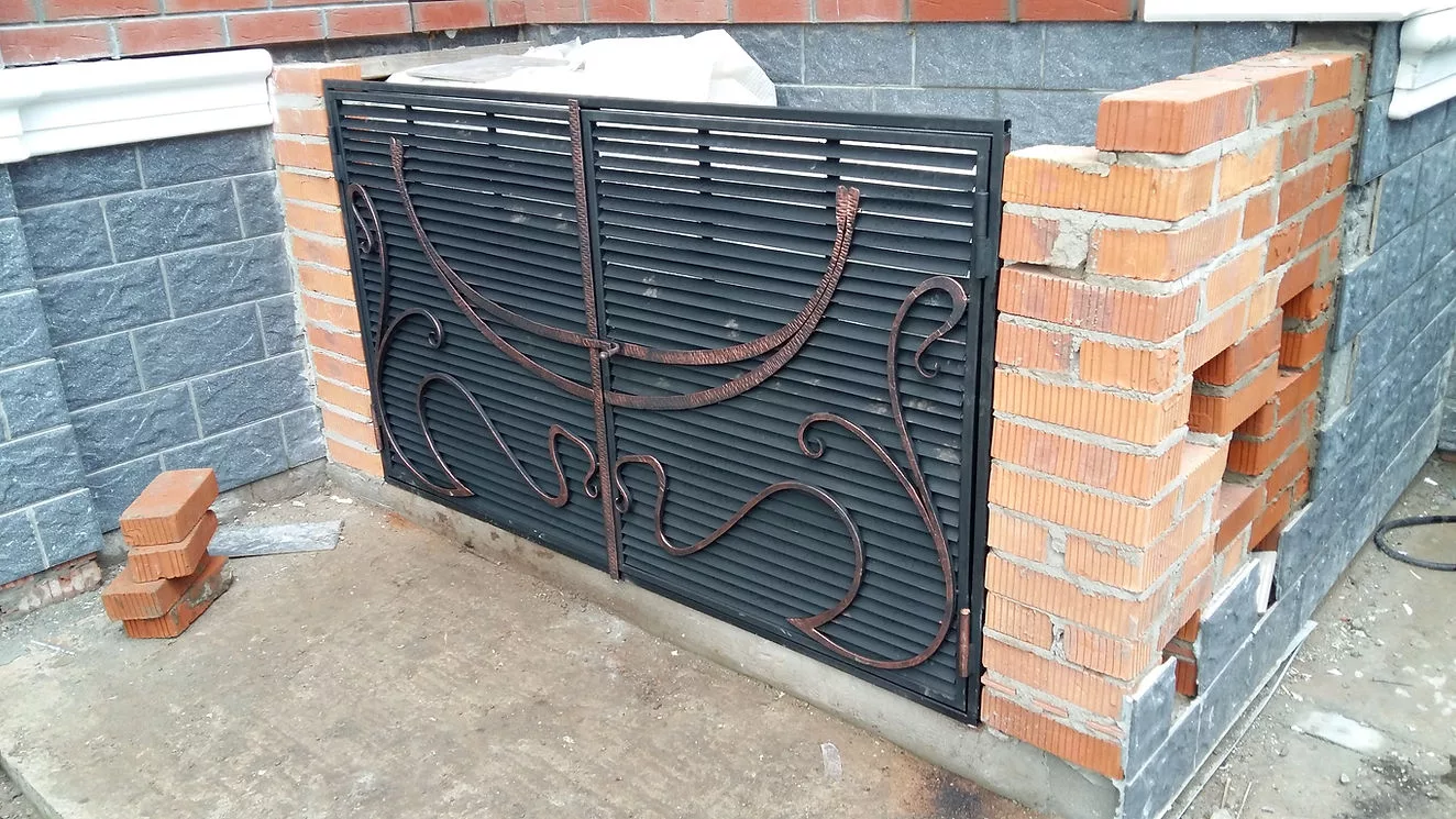 Кованая решетка на кирпичном фасаде здания.